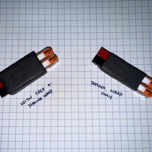 May include: Two black rectangular cases, one with shrink wrap and the other without. Each case holds two orange and white film canisters. Text on the image reads "With case shrink wrap" and "Shrink wrap only."