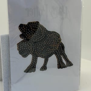 May include: A card featuring a dark brown illustration of a dog, possibly a Bloodhound, with a pattern of letters. The card is sealed in clear plastic. The words "Harry Potter" are visible in the background.