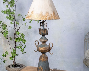 May include: A gold and blue table lamp with a white and gold lampshade. The lamp has a unique design with a decorative base and a finial.
