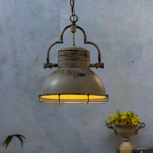 May include: A distressed white metal pendant light with a cage-like shade. The light is hanging from a chain and has a warm yellow glow.