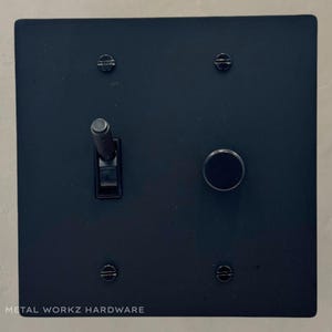 May include: Black metal light switch and dimmer with a toggle switch and a round knob. The switch plate has four screws and the text "METAL WORKZ HARDWARE" at the bottom.