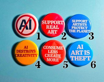 May include: Six circular badges with various slogans and designs. The badges are in red, blue, and yellow, with white text. The text includes phrases such as "Support Real Art" and "AI Destroys Creativity."