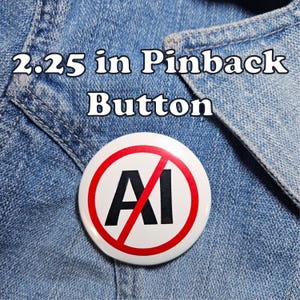 May include: A 2.25-inch pinback button with a white background and a red circle with a line through it. The letters "AI" are in black inside the circle. The text "2.25 in Pinback Button" is above the button.