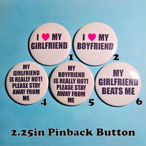 Può includere: Un set di sei spille rotonde bianche di 5,7 cm di diametro, con testo nero e un cuore rosa. Le spille presentano frasi come "I ❤️ MY GIRLFRIEND", "I ❤️ MY BOYFRIEND" e "MY GIRLFRIEND BEATS ME".