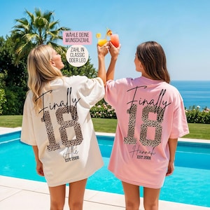 Op de afbeelding: Twee oversized T-shirts, één crème en één lichtroze, met de tekst "Finally 18" in zwart handschrift en grote cijfers met een luipaardprint. De shirts bevatten de namen "Allie" of "Hannah" en de tekst "EST.2008" in het zwart.