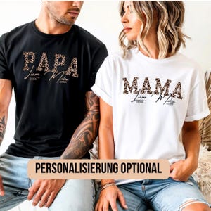 Op de afbeelding: Zwarte en witte t-shirts met luipaardprint tekst. Het zwarte shirt zegt "PAPA" en het witte shirt zegt "MAMA". Beide shirts hebben namen en het jaar "EST 2026" onder de hoofdtekst gedrukt. De tekst "PERSONALISIERUNG OPTIONAL" is gedrukt op een bruin banner.