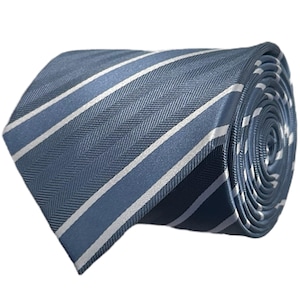 May include: A rolled necktie featuring a blue and slate grey herringbone weave pattern accented by thin, diagonal white stripes. The fabric has a smooth, slightly reflective finish, and the tie is coiled to display the layered texture and pattern.