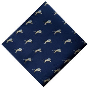 May include: Navy blue pocket square with a repeating pattern of tan and light blue lions. The lions are depicted in a running pose, creating a dynamic and stylish accessory.