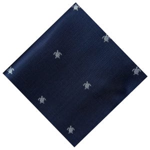 May include: Navy blue tie with a repeating pattern of small, silver sea turtles. The tie has a subtle ribbed texture and is displayed at a diagonal angle against a white background.