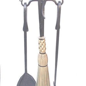 May include: Black metal fireplace tool set with a brush, shovel, and poker. The tools are mounted on a stand with a decorative scroll design.