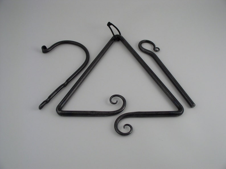 Puede incluir: Un carill&oacute;n de viento triangular de metal negro con dos varillas de metal colgantes. El tri&aacute;ngulo tiene un remolino decorativo en la parte inferior.