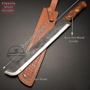 May include: A 17-inch long carbon steel blade with a burn ash wood handle. The blade is in a brown leather sheath with a decorative pattern. The text "Overall Length 17" is written on the sheath.