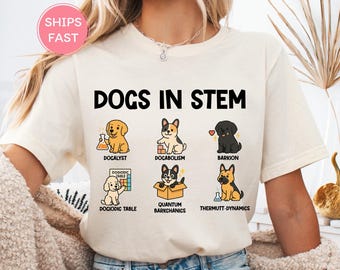 May include: Cream-colored t-shirt with the text "DOGS IN STEM" and illustrations of dogs representing scientific concepts. The shirt features various dog breeds with labels like "DOCALYST" and "BARKION".