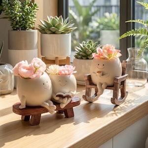 Puede incluir: Una colección de macetas de cerámica con caras sonrientes, con flores. Las macetas están sobre un banco de madera y una mecedora. Otras plantas suculentas están en macetas blancas y grises.