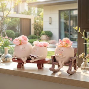 May include: Three whimsical, off-white ceramic planters shaped like smiling figures, each holding flowers. One sits on a red bench, another on a rocking chair, and the third on a bench. The planters are filled with pink flowers, creating a charming display.
