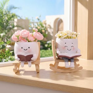 May include: Two white ceramic planters with smiling faces, each holding a book and filled with flowers. One sits on a small chair, the other on a rocking chair. The flowers are pink and white.