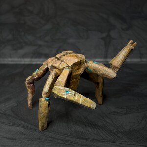 May include: A handcrafted, abstract sculpture of a multi-legged creature. The sculpture is primarily brown with blue accents, and has a textured, weathered appearance. The legs are positioned in a dynamic pose, suggesting movement.