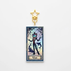 May include: A rectangular Vox keychain with a gold star-shaped clasp. The image features a cartoon character with a TV head, a red suit, and a blue background with lightning and dolphins. The word "Vox" is at the bottom.