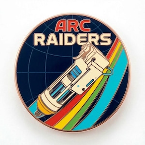 May include: A round pin with the text "ARC RAIDERS" in red and cream. The pin features a stylized ray gun design over a blue background with a world map grid and a rainbow stripe.