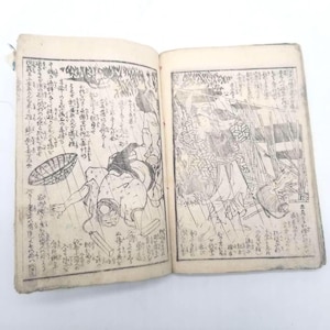 Puede incluir: Un libro antiguo abierto con dos páginas que presentan ilustraciones en blanco y negro grabadas en madera y texto en kanji japonés. La página izquierda muestra a una persona con una cesta, mientras que la derecha representa una figura cerca de una estructura.