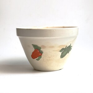 May include: Cream-coloured ceramic mixing bowl with a wide rim and a slightly tapered shape. The bowl features illustrations of a red pepper and a cucumber. The bowl has a vintage look with some discolouration.