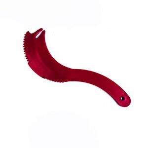 Puede incluir: Una herramienta de cocina roja y curvada con un borde dentado y una punta. El mango tiene un agujero en el extremo. La herramienta está diseñada para rebanar o cortar alimentos.