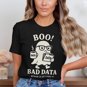Può includere: T-shirt nera con una grafica bianca di un fantasma con occhiali, che tiene una tazza e una cartella, entrambe con l'etichetta "DATA". Il testo "BOO! BAD DATA prove it or lose it" è sopra e sotto l'illustrazione.