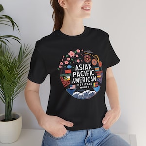 Könnte beinhalten: Schwarzes T-Shirt mit einem farbenfrohen Grafikdesign, das einen Kreis mit dem Text "Asian Pacific American Heritage Month" und verschiedenen Flaggen und Symbolen zeigt.