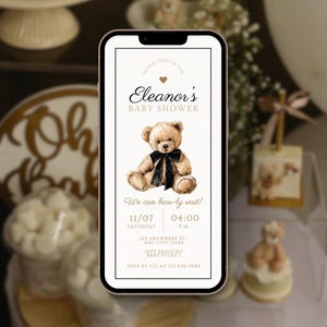 Könnte beinhalten: Babyparty-Einladung auf einem Smartphone. Die Einladung zeigt eine Illustration eines Teddybären mit schwarzer Schleife. Der Text lautet "Eleanor's BABY SHOWER" und "We can bear-ly wait!" mit Veranstaltungsdetails.