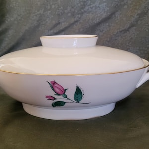 May include: White ceramic serving bowl with a gold rim and a floral design featuring pink roses and green leaves. The bowl has a lid.