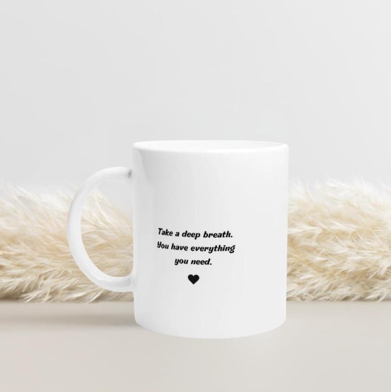 May include: White ceramic mug with a black inspirational quote that reads "Take a deep breath. You have everything you need." and a small black heart.