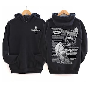 May include: Black hoodie with a front pocket and a white graphic of a cross made of nails. The back of the hoodie features a detailed illustration with the text "FORGIVE HIM, FATHER..." and a depiction of a crown of thorns.