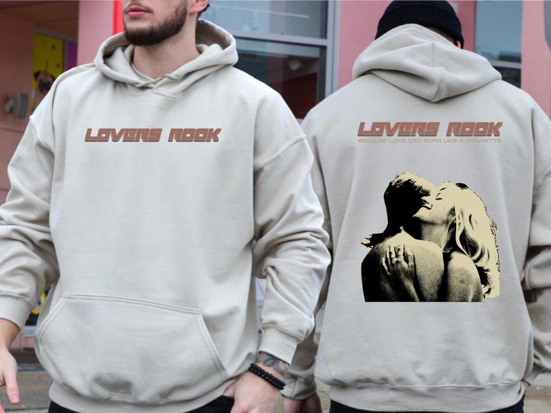 May include: Two beige hoodies with the text "Lovers Rock" printed on the front. One hoodie features a graphic of a couple embracing. The text below the graphic reads "Because love can burn like a cigarette."