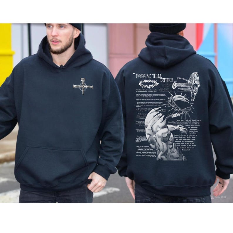 May include: Navy blue hoodie with a front pocket and a hood. The front features a silver cross design. The back of the hoodie has a detailed graphic with the text "Forgive Them, Father" and religious imagery. The hoodie is made of a soft material.