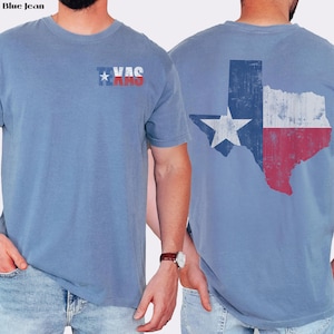 May include: Blue jean short-sleeve t-shirt featuring the Texas state flag design. The front of the shirt displays the word "Texas" with a star graphic. The back of the shirt features a distressed Texas flag graphic.
