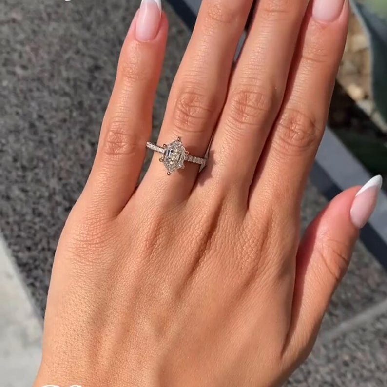 Stunning 2 carat hexagon cut lab grown diamond ring with a hidden halo, handcrafted in solid 14K gold. Modern and ethical engagement ring featuring a moissanite wedding band for added sparkle. Ideal for proposals, anniversaries, or as a unique promise ring. Sleek, geometric design for the contemporary bride. Sustainable and luxurious fine jewelry gift for her, available in rose, white, or yellow gold.