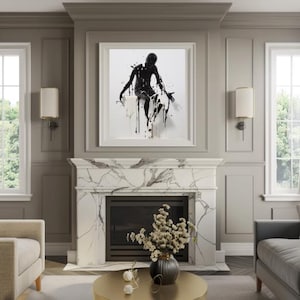 Puede incluir: Una obra de arte abstracta enmarcada que presenta una figura negra con pintura goteando. La obra de arte se exhibe sobre una chimenea de mármol, con una mesa de centro dorada y muebles de tonos neutros. La habitación tiene paredes grises y molduras blancas.