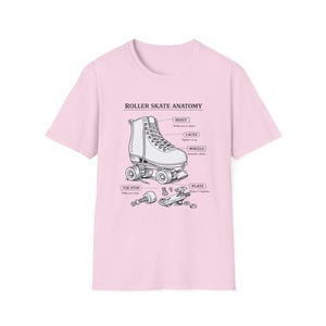 May include: A pale pink t-shirt displays a diagram of a roller skate, labelled "Roller Skate Anatomy." The diagram shows the boot, laces, wheels, toe stop, and plate. The text is black, and the roller skate is white.
