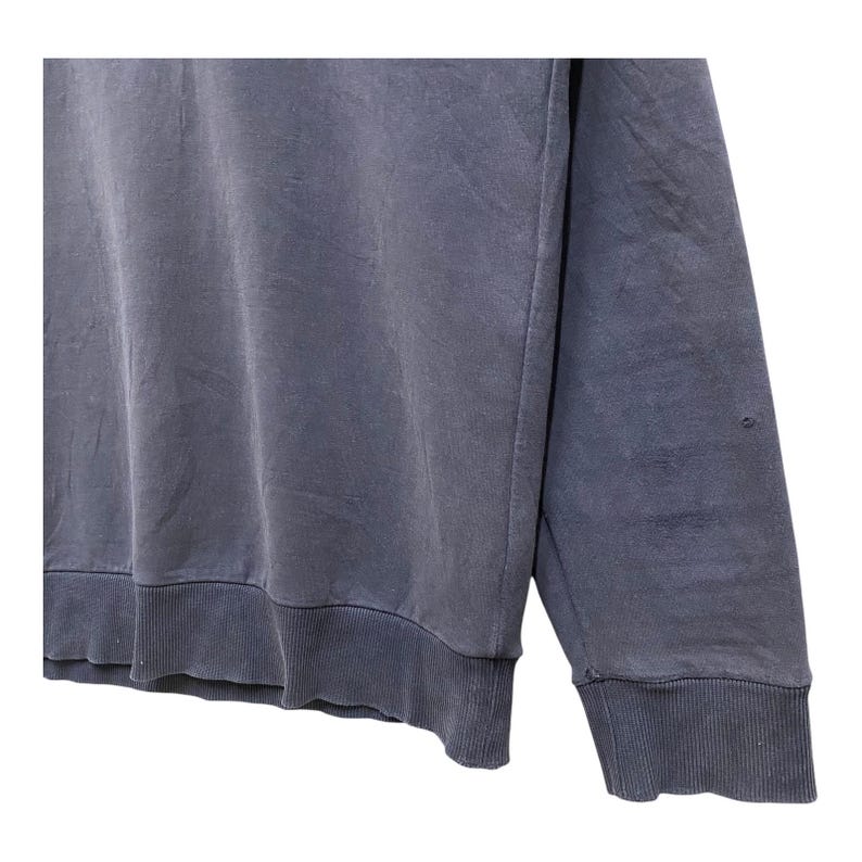 May include: A faded blue sweatshirt with ribbed cuffs and hem. The long-sleeved top has a crew neck and a slightly worn appearance. The fabric appears soft and comfortable, suitable for casual wear.