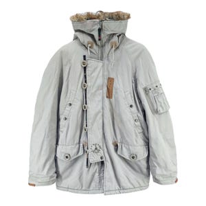 Może przedstawiać: Jasnoszara zimowa parka z kapturem podszytym sztucznym futrem. Kurtka posiada liczne kieszenie, zapięcie na guziki i zamek błyskawiczny oraz skórzane naszywki. Parka ma solidny, użytkowy design, odpowiedni na zimną pogodę.