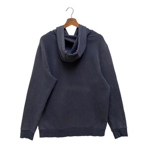 May include: A dark grey hoodie with a drawstring hood, long sleeves, and a kangaroo pocket. The hoodie is hanging on a wooden hanger against a white background. The fabric appears to be a soft, comfortable material.