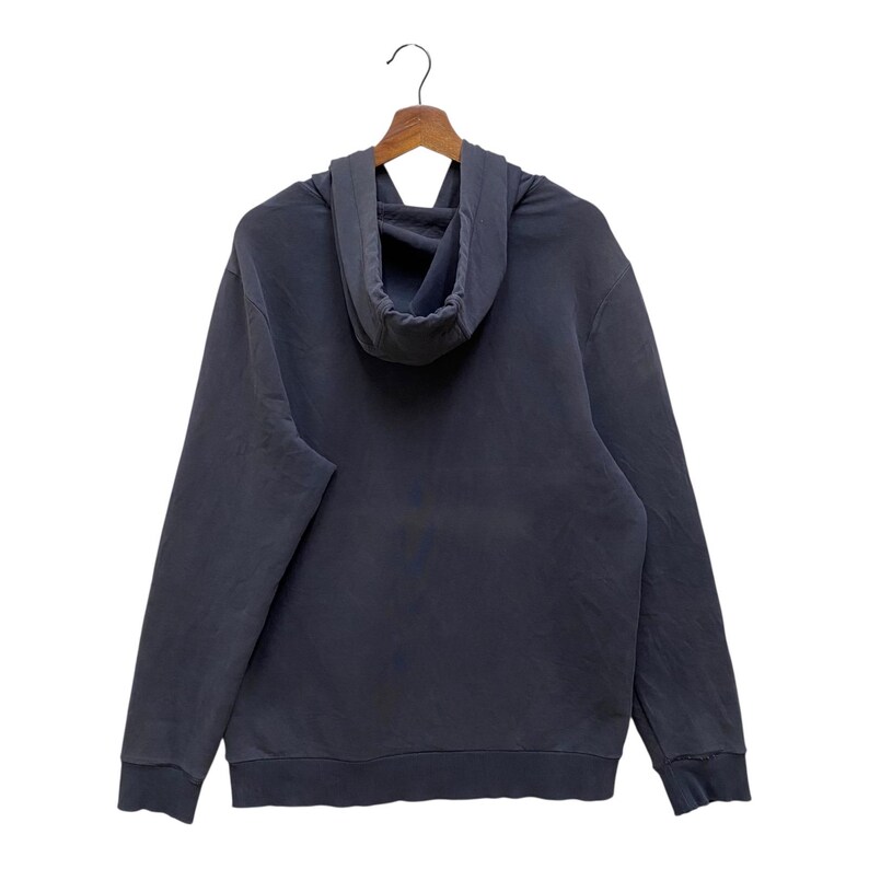 May include: A dark grey hoodie with a drawstring hood, long sleeves, and a kangaroo pocket. The hoodie is hanging on a wooden hanger against a white background. The fabric appears to be a soft, comfortable material.