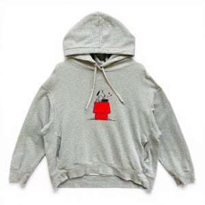 Peut inclure: Un sweat à capuche gris avec un motif Snoopy. Le motif montre Snoopy assis sur son niche rouge avec des coeurs. Le sweat-shirt a une capuche à cordon et une poche kangourou.
