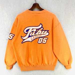 以下が含まれることがあります： オレンジ色のスウェットシャツで、背面に白と青のFubu League 05のグラフィックがプリントされています。