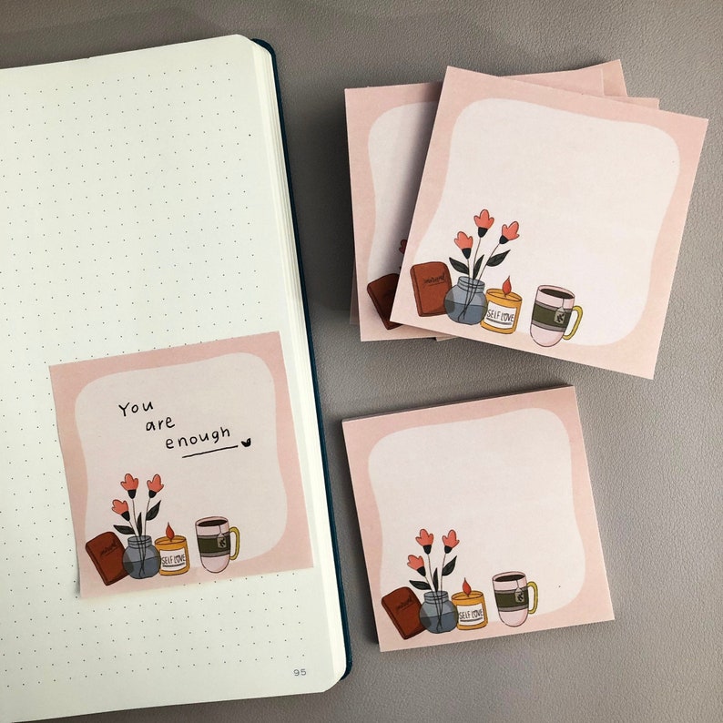 May include: Pink sticky notes with a white center and a light pink border. Each note features a drawing of a vase of flowers, a candle, a mug, and a book. One note has the text "You are enough" with a heart symbol.