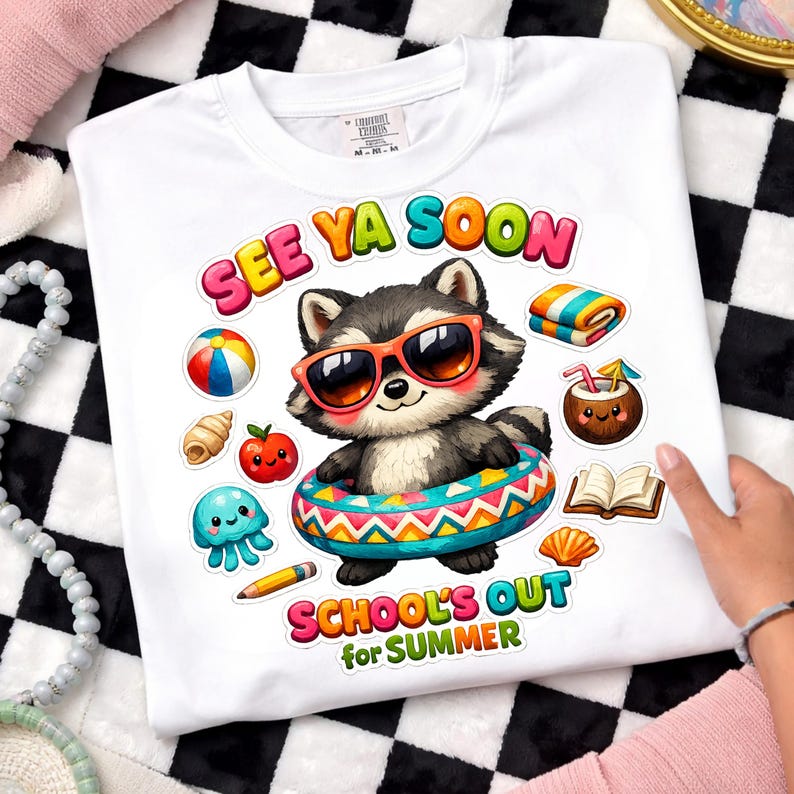 May include: White t-shirt with a colorful graphic of a raccoon wearing sunglasses and an inner tube. The text "SEE YA SOON" and "SCHOOL'S OUT for SUMMER" are displayed above and below the raccoon, along with other summer-themed illustrations.