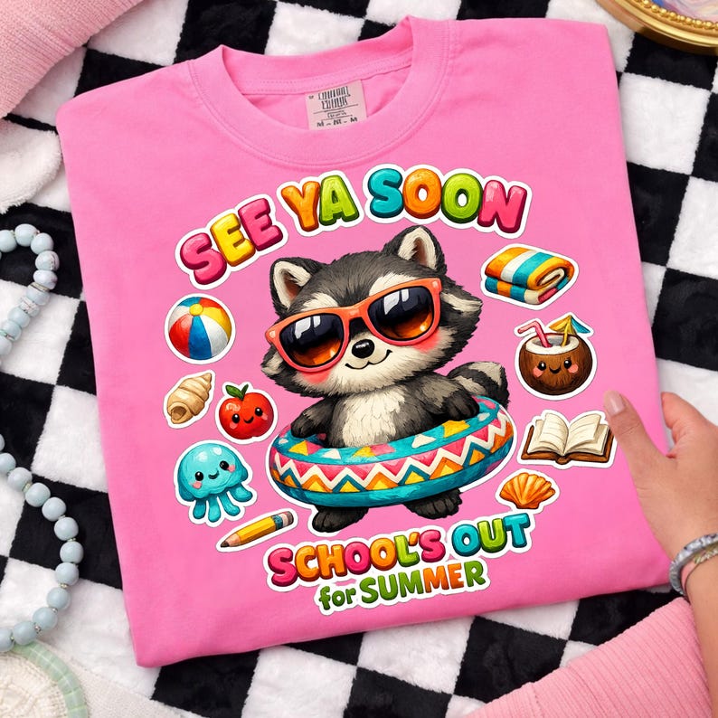 May include: Pink t-shirt with a graphic of a raccoon wearing sunglasses and an inner tube. The text "SEE YA SOON" and "SCHOOL'S OUT for SUMMER" are printed on the shirt, along with beach-themed illustrations.