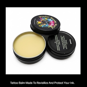 Puede incluir: Una lata redonda de metal negro que contiene bálsamo para tatuajes de color amarillo pálido, con una tapa negra separada que muestra el texto Wonder World Tattoo Balm y una segunda tapa negra con ingredientes e instrucciones para el bálsamo de coco.