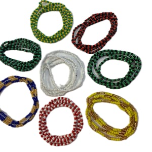 Peut inclure: Un assortiment de colliers de perles de différentes couleurs, dont vert, jaune, rouge, blanc et bleu. Les colliers sont disposés en cercle sur un fond blanc. Ces colliers colorés sont probablement utilisés à des fins spirituelles ou décoratives.