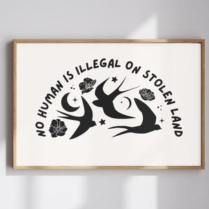 Pode incluir: Impressão em preto e branco com o texto "No human is illegal on stolen land" em arco. O texto é rodeado por pássaros pretos estilizados e flores.